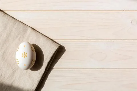 A single decorated Easter egg rests on a linen napkin on a wooden table Stock Photos