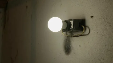 Single Dim Light Bulb on Dark Textured Wall in Abandoned Room Vídeos de archivo 335636567
