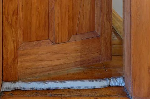 A single draft excluder sits on the floor, the door is open behind it Foto stock