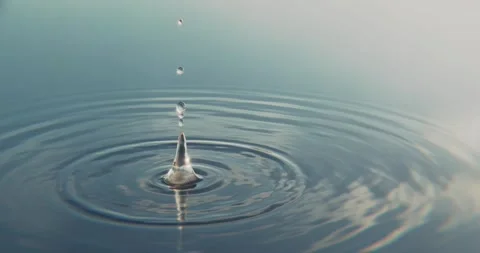 A single drop of water falls into a calm, mirror-like surface of the sea Video stock 283641685