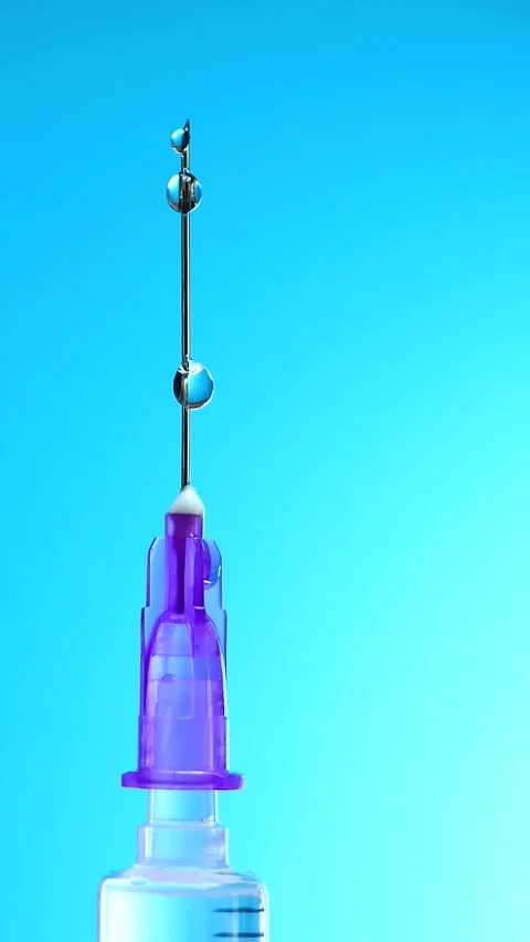 Single droplet at end of syringe needle, reflecting ambient light Stock Footage 323259587
