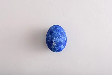 Single Easter egg in the color of the year-classic blue on white background Stock Photos