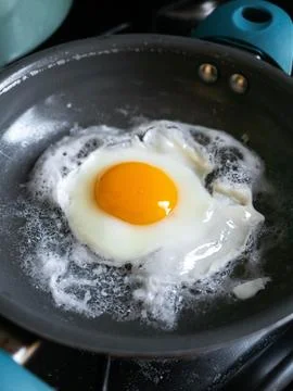Single egg sizzles gently in a pan Foto stock