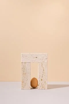 Single egg standing in a travertine marble blocks doorway. Stock Photos