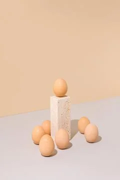 Single egg standing on a travertine marble block podium surrounded by group. Stockfoto's