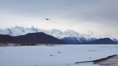 Single Engine Bush Plane Soars Banking over River &amp; Mountains in Alaska Winter Video stock 107800972