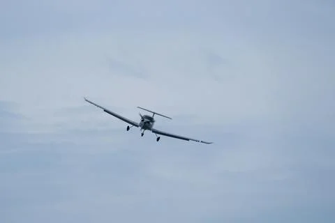 Single-engine plane approaching the airport under a cloudy sky Stock Photos