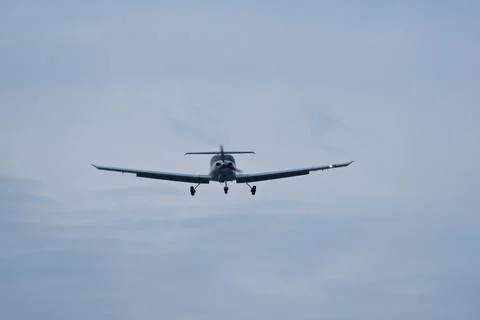 Single-engine plane approaching the airport under a cloudy sky Stock Photos