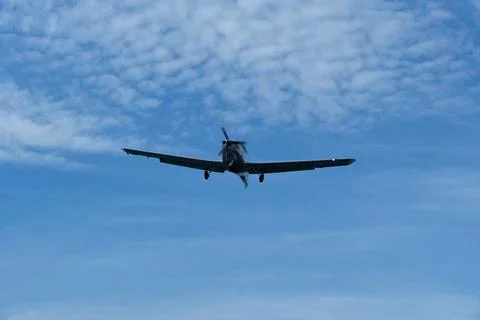 Single-engine plane approaching the airport under a cloudy sky Stock Photos