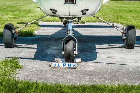Single engine plane wheels and landing gear on parking pad with wheel chocks. Stock Photos