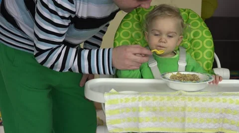 Single father teaching feeding his baby daughter with spoon in hand. Stock Footage 62174802