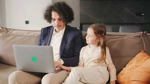 Single father working from home using laptop, distracted by noisy little Stock Footage 278607946