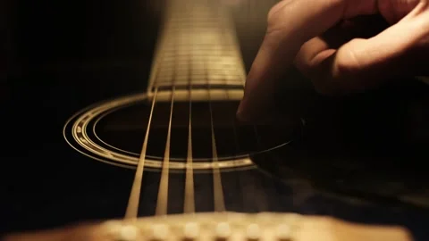 Single Finger Touches Strings of a Guitar with Dark Light Background Stock Footage 303755031