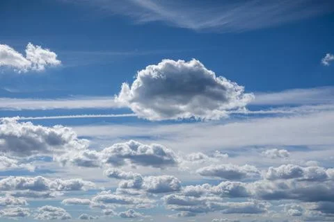 Single fluffy cloud floating in a bright blue sky. Stock Photos