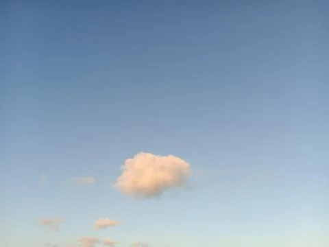 Single fluffy cloud in the vast clear blue sky Фото