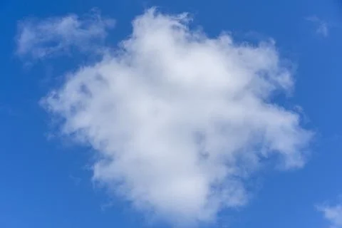 Single fluffy white cloud isolated in a bright blue sky on a sunny day Stock Photos