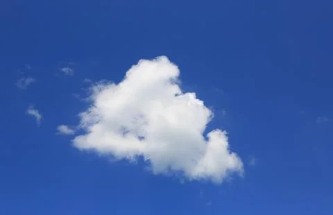 A single fluffy white cumulus cloud floats in a clear blue sky 写真素材