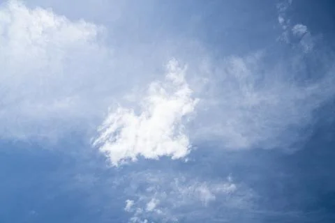 Single fluffy white cumulus cloud floating in a hazy blue sky Fotos Stock