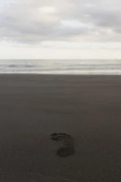 A single footprint is left on the sandy beach, with the vast ocean stretching Stock-Fotos