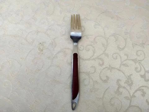 Single fork with red handle on light textured background Photos