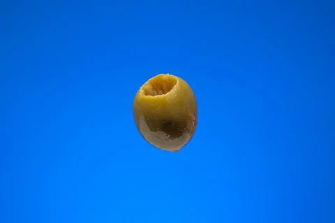 Single fresh green olive without seed. Close up studio shot, isolated on blue Stock Photos