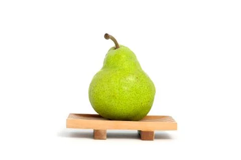 Single fresh Packham pears fruit above square wooden plate isolated on white  Stock Photos