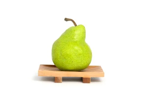 Single fresh Packham pears fruit above square wooden plate isolated on white  Stock Photos