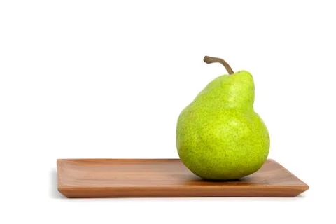 Single fresh Packham pears fruit above square wooden plate isolated on white  Foto stock
