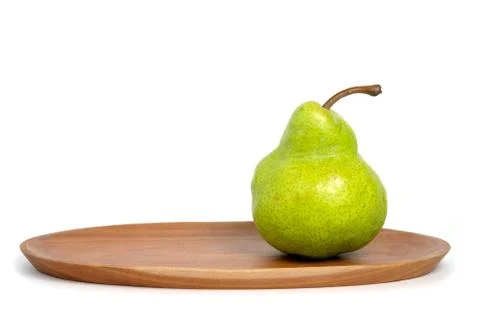 Single fresh Packham pears fruit above oval wooden plate isolated on white ba Stock Photos