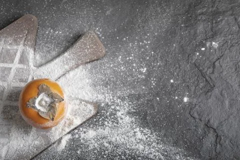 Single fresh persimmon fruit with flour on wooden board Stock Photos