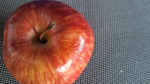 Single fresh red apple sitting on a textured gray surface Stock Photos