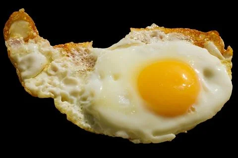 Single fried egg isolated on black background. Stock Photos