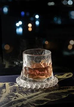 A single glass of bourbon rests gracefully upon a beaded glass coaster, whe.. Foto stock