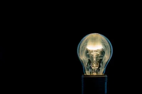 Single glass bulb mounted in socket with flame inside Stock Photos