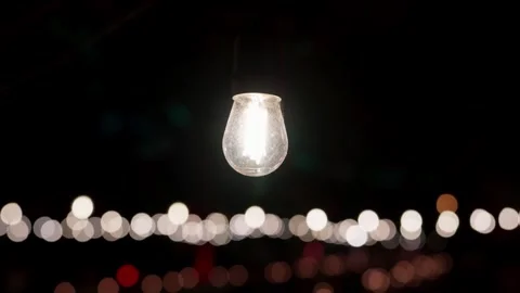 Single Glowing Festoon Bulb Above a Row of Blurred Lights at Night Stock Footage 342330972