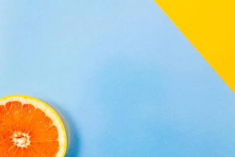 Single grapefruit slice close-up on blue and diagonal yellow background To... Foto stock
