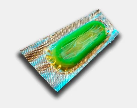 SINGLE GREEN CONDOM IN FOIL WRAPPER ON WHITE BACKGROUND Stock Photos