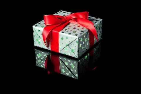 Single green gift box with red ribbon bow on black reflective surface. Gift b Stock Photos