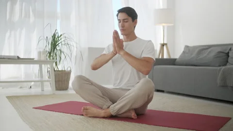 Single Guy Doing Yoga at Home Keeping His Eyes Closed Breathing Slowly. Sport at Видео 134707075
