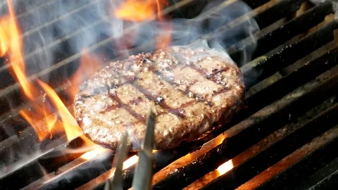 Single hamburger is cooking on the grill Stockbeeldmateriaal 98395577