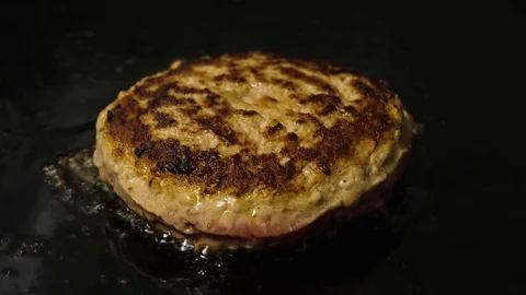 Single hamburger patty grilling on the frying surface with oil, 4K 60 FPS Stock Footage 76897499