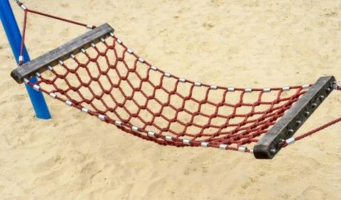 Single hammock made from string mesh with a sand background. Summertime image Stock Photos