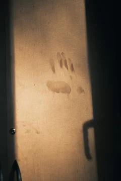 A single handprint appears on a dusty surface, partially lit by warm sunlight Stock Photos