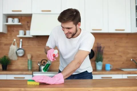 Single handsome man cleaning kitchen at home. Stock Photos