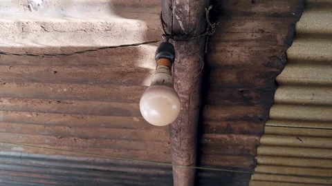 Single Hanging Light Bulb in Rustic Home Interior with Corrugated Metal Roof Stock Footage 335149315