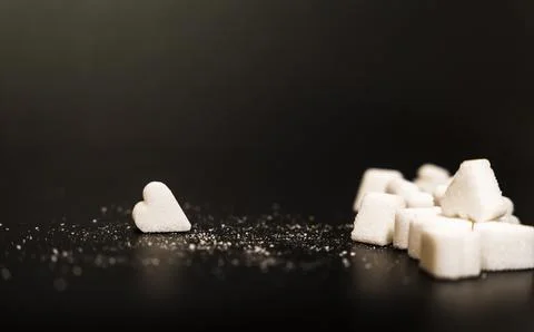 Single heart-shaped sugar cube standing out from a pile of regular sugar cubes, Stock Photos
