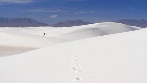 A single hiker climbing a large white sand dune. Stock Footage 119790165