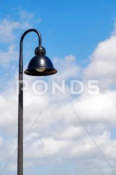 A single hooded street light with blue sky background Stock Photos