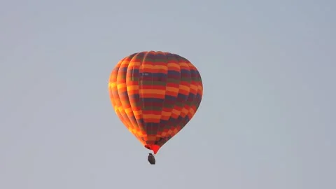 Single hot air balloon floats against a clean blue sky - Open Air and Soft Light Stock Footage 339748201