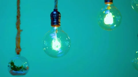 A single illuminated light bulb hangs from rope against a vibrant green wal.. Stock Footage 341801452
